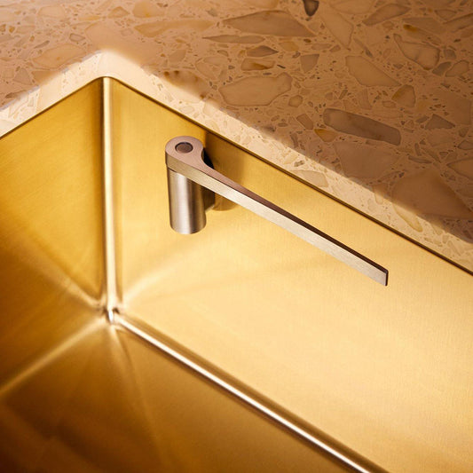 Disktrasehållare i Rostfritt Stål som är fäst i en diskho i guld i ett modernt kök.